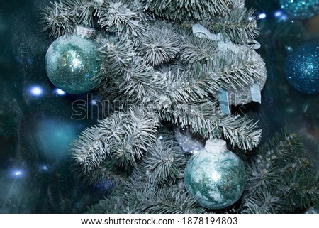 Snow-covered artificial Christmas tree with frost and blue-blue decorations. Christmas background