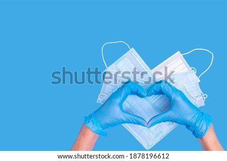 Medical gloves blue Heart shaped hand symbol on heart shaped medical protective masks on blue background with copy space. Healthcare concept