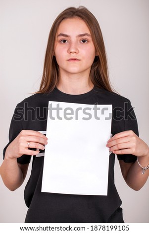 Portrait of a young girl with a blank sheet of paper - place for an inscription