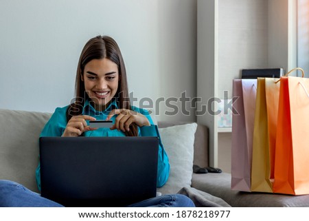 Shot of a cheerful young woman relaxing on sofa while doing online shopping on a laptop at home. Photo of an attractive young woman using a digital tablet and credit card on the sofa at home.