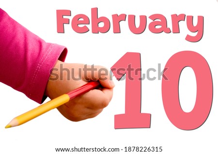 Children's hand writes February 10 in red pencil. White background with winter date, business and holiday concept.