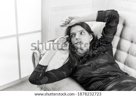 Studio portrait of young beautiful woman laying on sofa
