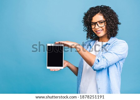 Happy young beautiful afro american woman showing blank tablet computer isolated over blue background. 