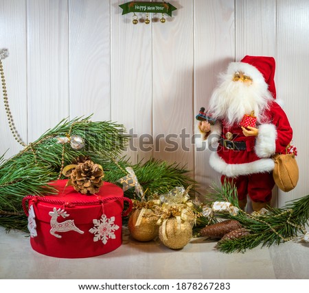 Merry New Year mood. Santa Claus doll, New Year's decor, branches of a Christmas tree and a gift in a red box. Horizontal photo, macro. Kyiv (Kiev), Ukraine, Europe.