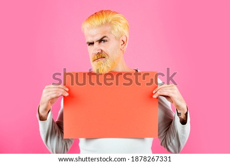 Serious caucasian blond male model posing in fashion concept studio shoot. Man worker holding advertising red board