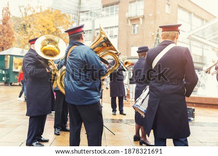 Street artists military marching band performance instruments, trumpets and drums for audience gathered on street, orchestra playing in public square on rainy day dressed in uniform in England