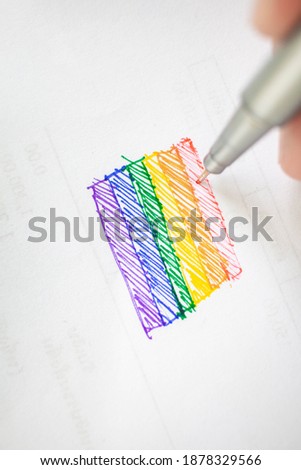 A male hand is drawing an LGBT flag