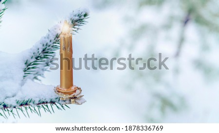 Photo Christmas decoration in the form of a candle on a spruce branch covered with natural snow. Winter christmas picture
