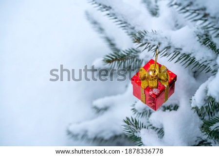 Photo Christmas decoration in the form of a gift on a spruce branch covered with natural snow. Winter christmas picture