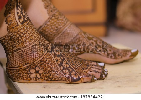  Picture of bridal Mehndi for wedding ceremony. Henna Mehndi on Bride feet on a small height table at Indian wedding ceremony. Front foot is focused and other is defocused. Selective focus concept.