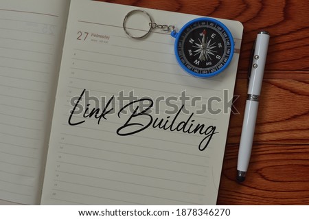 Top view of pen, compass and notebook written with text LINK BUILDING. Business concept.