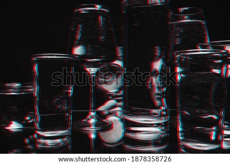 surreal strange portrait of a man looking through a magnifying glass and glasses of water with reflections and distortions. Black and white with 3D glitch virtual reality effect