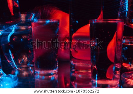 psychedelic portrait of a mad man schizophrenic looking through glasses of water with blur and red and blue neon lights