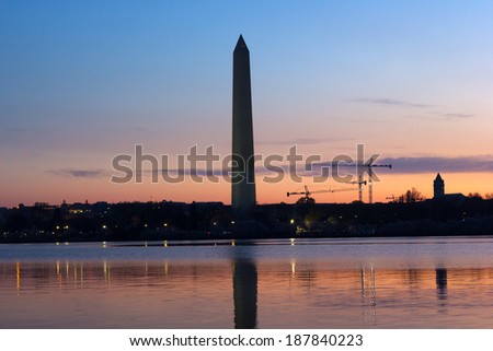 Washington Monument at dawn with city skyline on background. Colorful reflections in Tidal Basin waters.