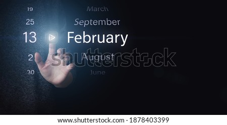 February 13rd. Day 13 of month, Calendar date. Hand click luminous icon PLAY and DATE on dark blue background. Winter month, day of the year concept
