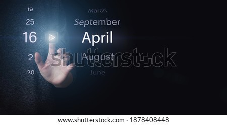 April 16th. Day 16 of month, Calendar date. Hand click luminous icon PLAY and DATE on dark blue background. Spring month, day of the year concept