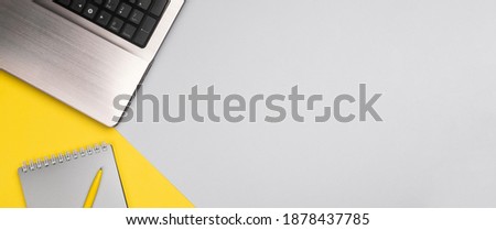 Business background with laptop and notepad. Minimal stylish workspace in new color of the year 2021: Ultimate gray and Illuminating yellow. Top view, flat lay, copy space, banner