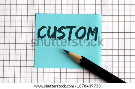 CUSTOM , the phrase is written on colored stickers, on notepad background. Business concept