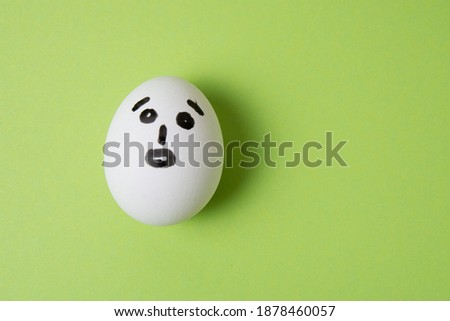 Egg with a surprised face, on a green background with place for text