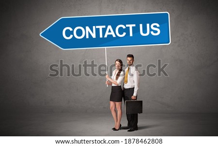 Young business person in casual holding road sign with CONTACT US inscription, new business direction concept