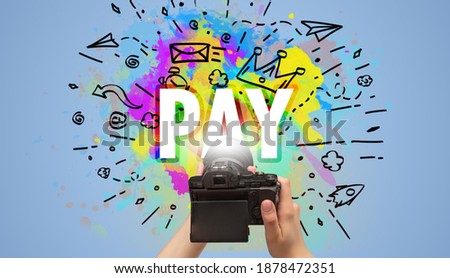 Close-up of a hand holding digital camera with abstract drawing and PAY inscription