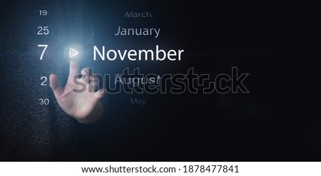 November 7th. Day 7 of month, Calendar date. Hand click luminous icon PLAY and DATE on dark blue background. Autumn month, day of the year concept