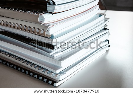 Stack of report papers lies on a desk ready for review Royalty-Free Stock Photo #1878477910