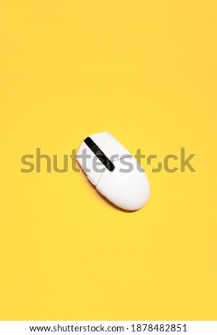 Vertical flat lay photo of a white plastic computer mouse on an isolated yellow background.