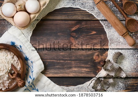 Flour scattered in the form of a circle, rolling pin and white linen napkin on an old wooden background. Place for text. Background for baking. 