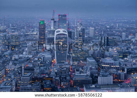 Illuminated London City skyline at dusk blue hour from above in a cloudy day