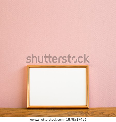 Empty picture frame on wooden table. pink background