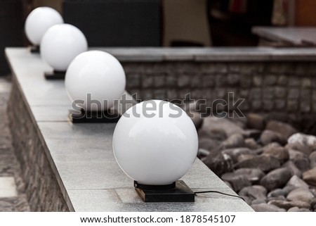 row balls street lantern on granite stone parapet on backyard terrace, lighting object closeup, nobody. Royalty-Free Stock Photo #1878545107