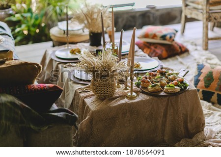 table decorated with white tablecloth and food, boho items, flowers and vintage antique tableware
