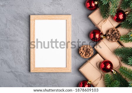 Christmas holidays composition with picture frame mockup. Red baubles, gifts and fir-tree branches.