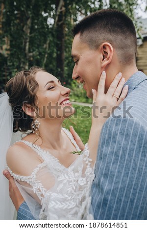 Wedding portrait of a stylish groom and beautiful bride in a white lace dress outdoors in the forest. Hugging newlyweds.