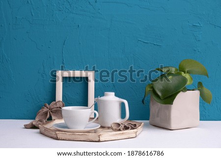 white frame for photo, home plant and breakfast with coffee on a tray on a blue background on the table