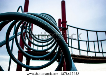 Playground, circle climbing frame with a bridge. Abstract and artsy angle with blue and red themed edit. 