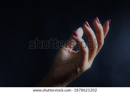 Woman hand red  nail in the dark light. stock photo 