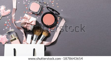 Long wide banner with gift paper bag with make up tools and set of decorative cosmetic on trendy gray background . Valentine’s Day present idea. Festive beauty blog cover concept.