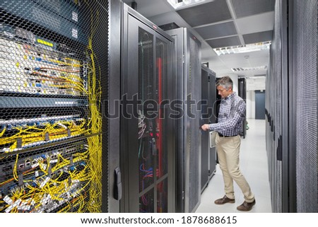 Technician With Laptop Working opening the locked door of the server In the secured data center