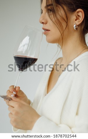 Photo portrait of dreamy model looking blank space keeping glass of red wine wearing stylish clothes isolated white color studio background