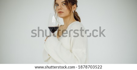 Cropped photo portrait of pretty model looking at side holding red wineglass wearing white sweater isolated on white color studio background