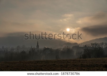 the sun breaking through the clouds just above the forest-covered mountains