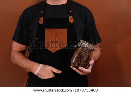 Barista holds glass jar full of coffee beans