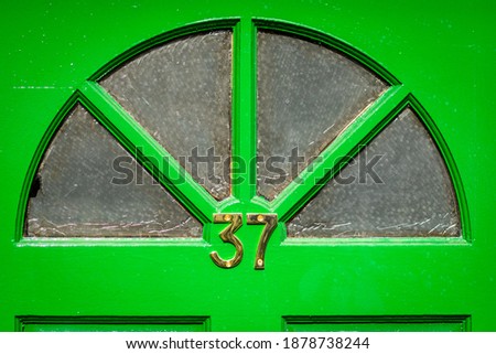 37 in golden digits on a bright green wooden front door