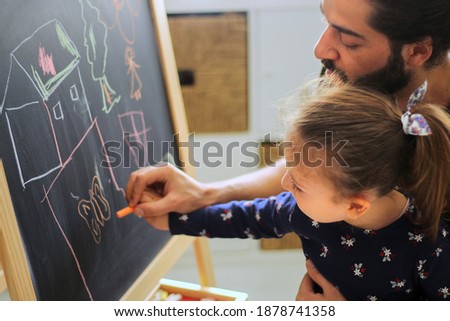
little girl learning to draw with her father. Drawing activity at home