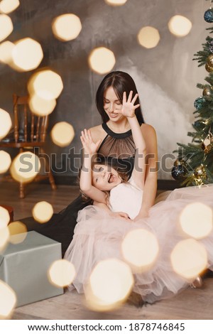 People reparing for Christmas. Mother playing with her daughter. Family is resting in a festive room. Little girl in a pink dress.