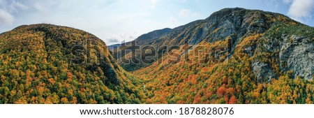Panoramic view of peak fall foliage in Smugglers Notch, Vermont. Royalty-Free Stock Photo #1878828076