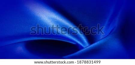 Blue silk fabric. Panoramic photo. Atlas is a beautiful and royal silk fabric. Has a shimmering glitter, texture, background, pattern.