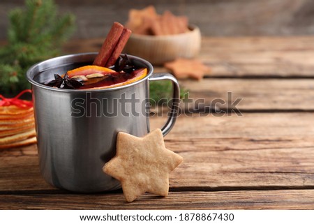 Aromatic mulled wine and cookie on wooden table, closeup. Space for text